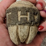A wooden Metroid carved from a piece of driftwood, with Zebeth and a heart carved into the side