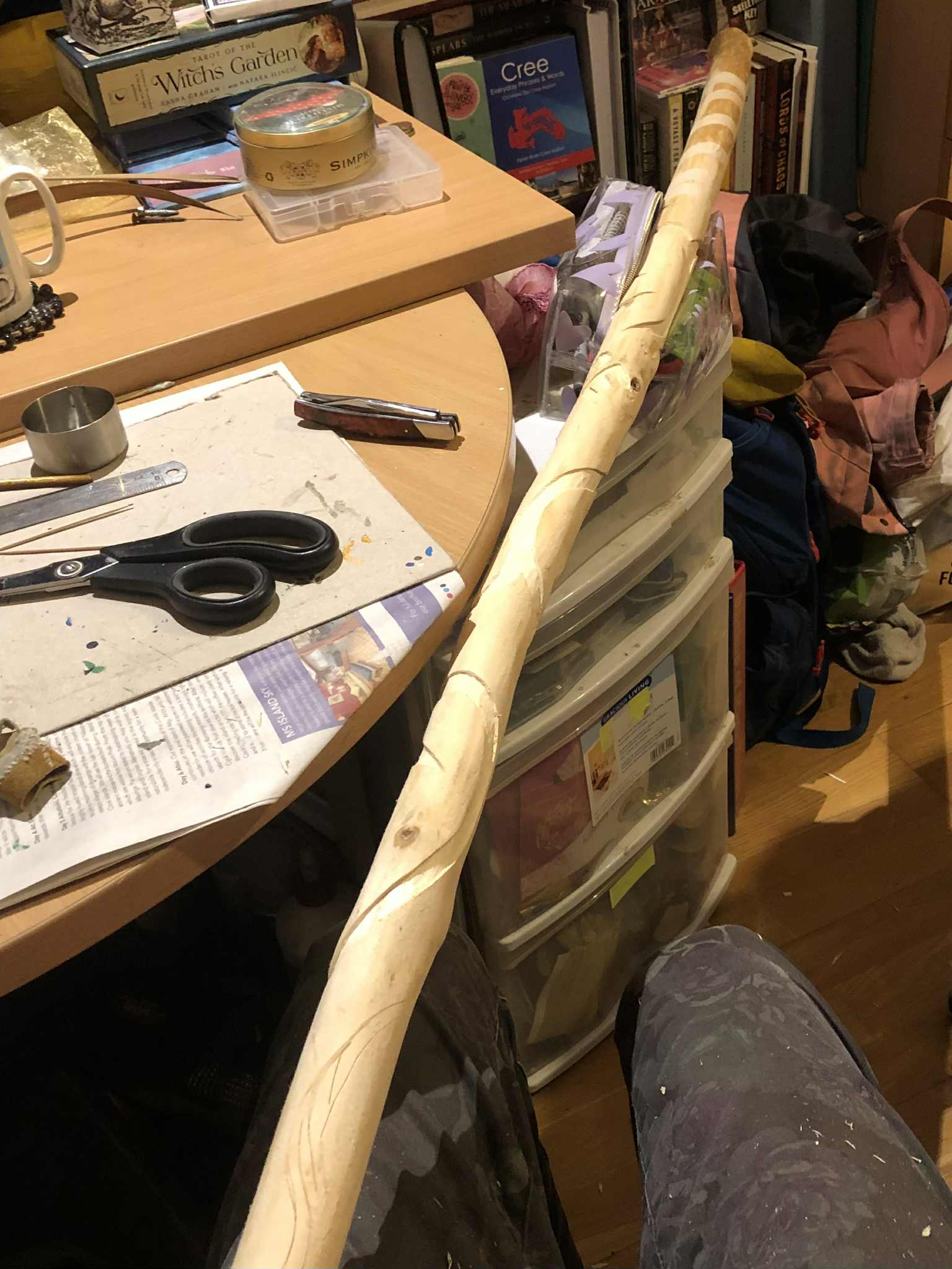 The bottom length of the staff held out, showing that the majority of the linework has been carved in, and what isn't carved out has been etched in visible lines.