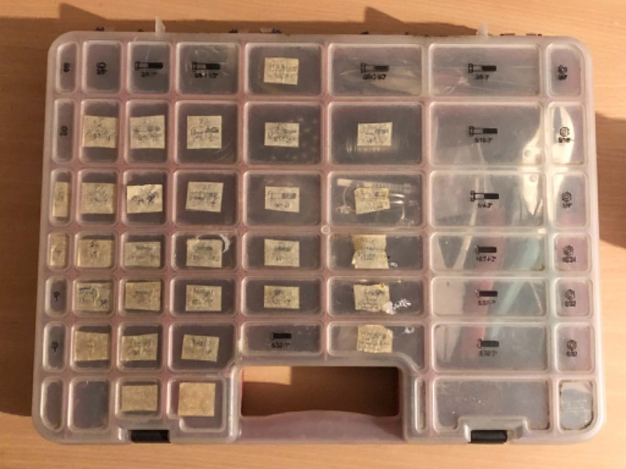 My original chainmailling kit, labelled with barely readable painters tape squares, sitting on a wooden table.