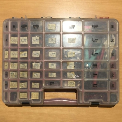 A red craft nuts and bolts organizer case, with tape labels over about two thirds of the slots, and many of the remaining slots being combined to fit pliers and other tools.