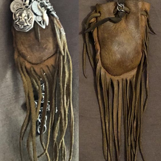 A worn leather medicine bag with fringes hanging down, right after having been conditioned from years of use.