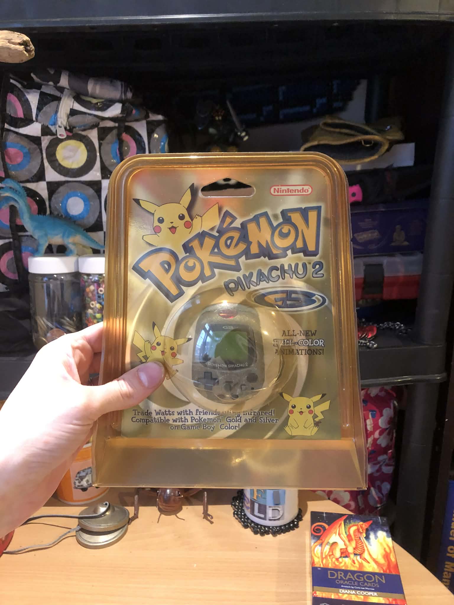 Kabutroid holding up a sealed copy of a Pokemon Pikachu 2 GS pedometer toy.