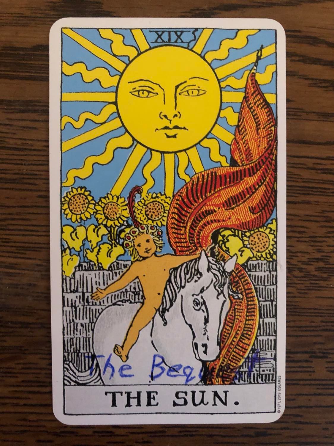 The sun card with the bequest written on it, laying on a wooden desk.