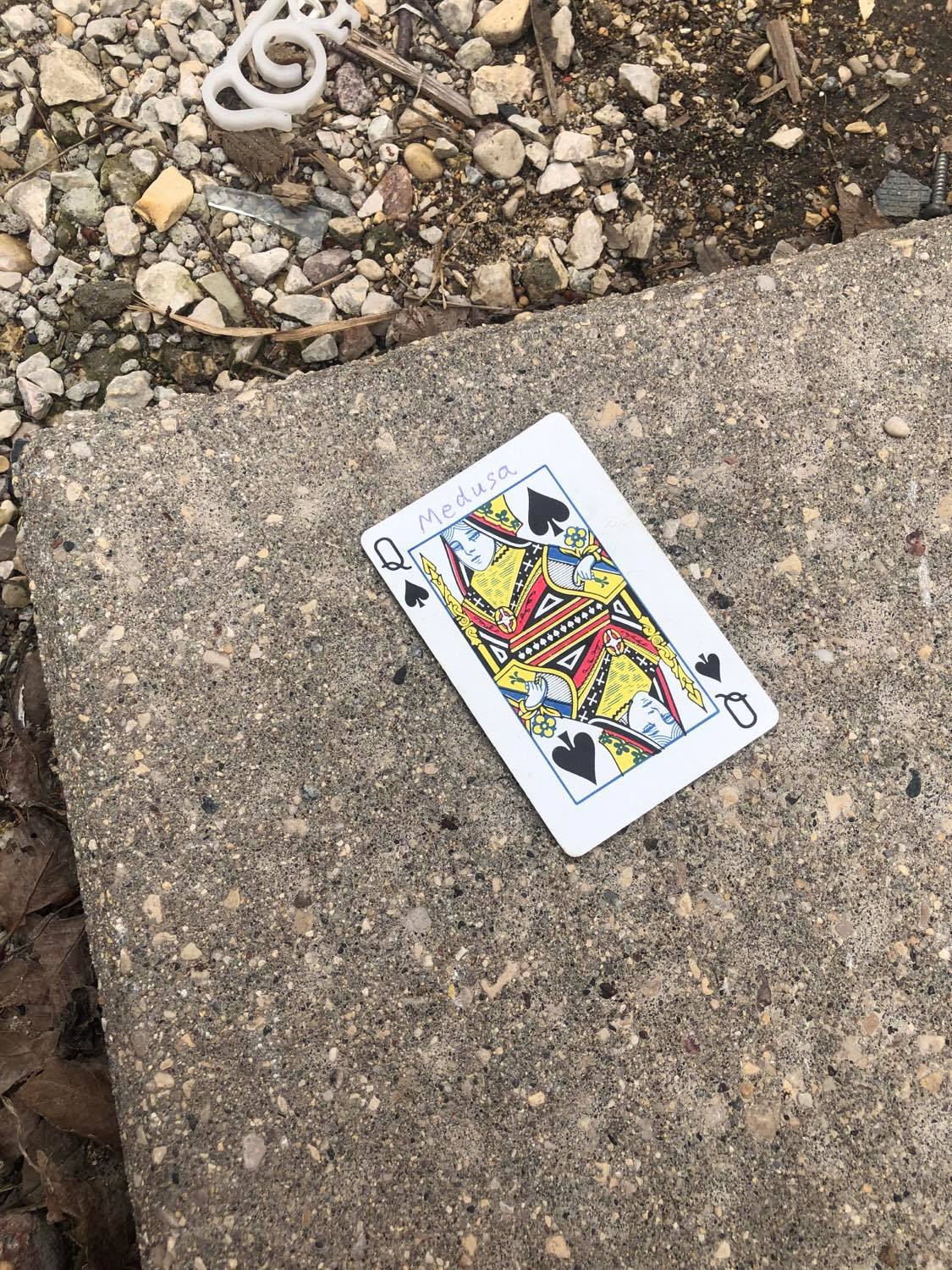The queen of spades, laying on the ground before the creature.