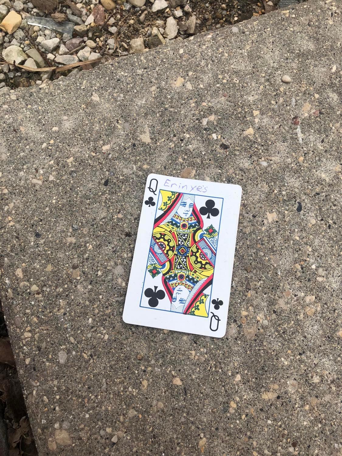 The queen of clubs, laying on the ground before the creature.