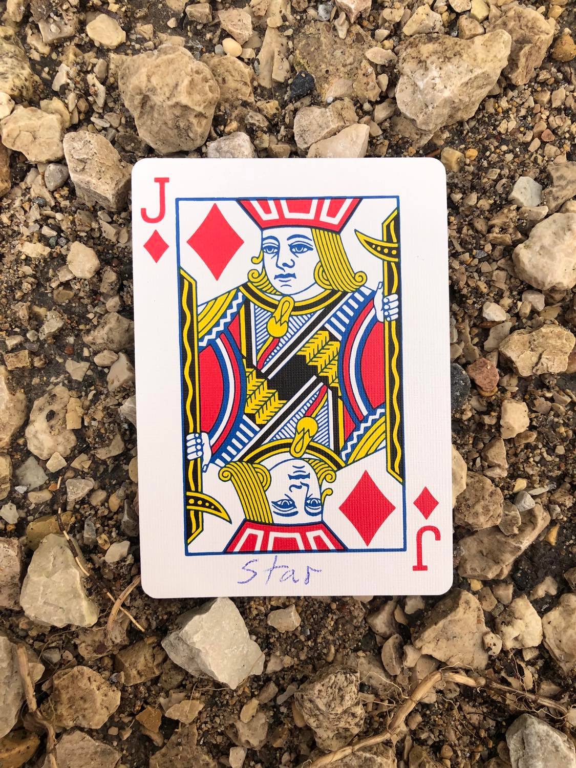 The jack of diamonds with Star written on it, laying on the gravel path.
