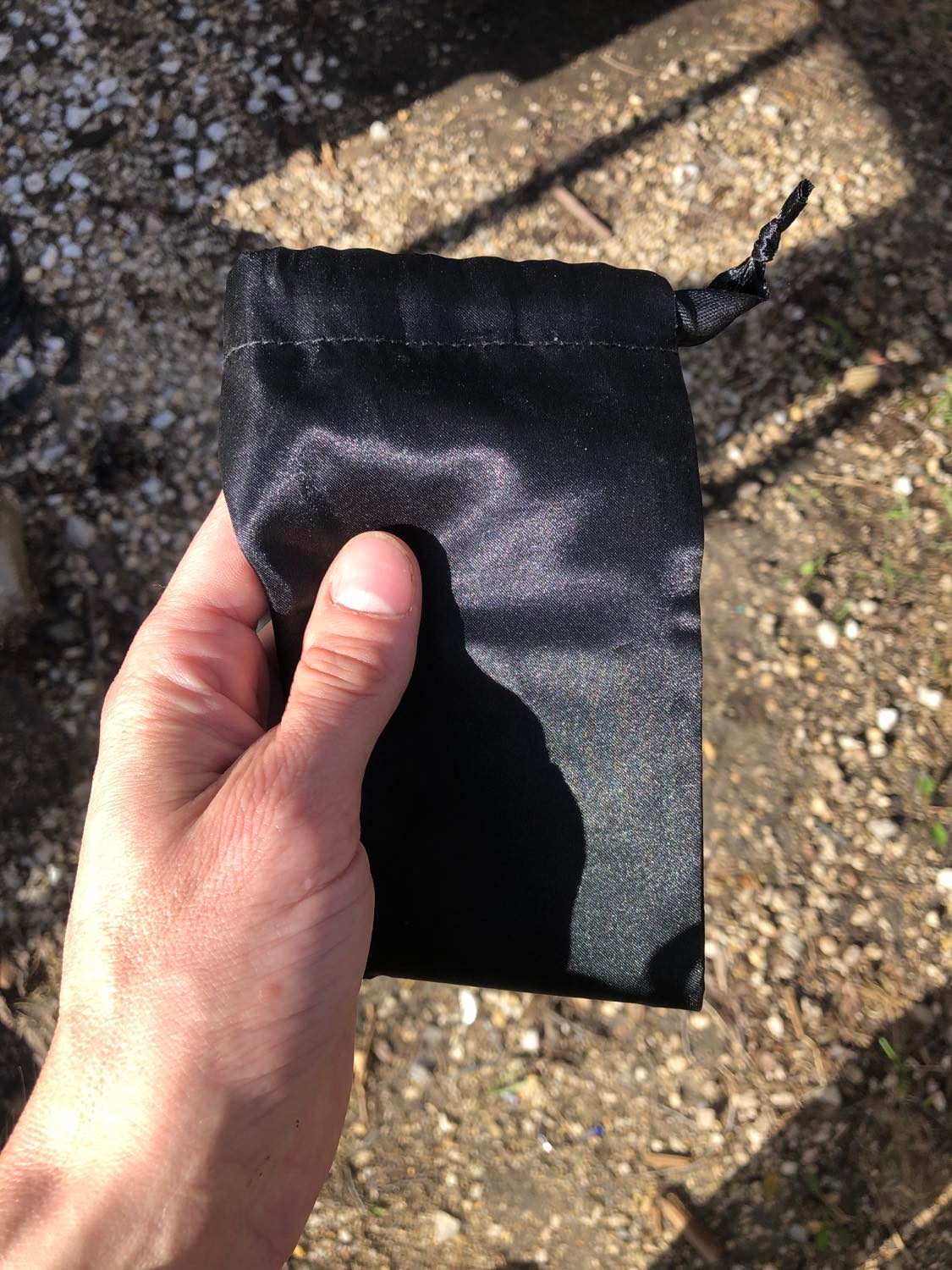 A black velvet pouch, held in front of you on a well-worn path.