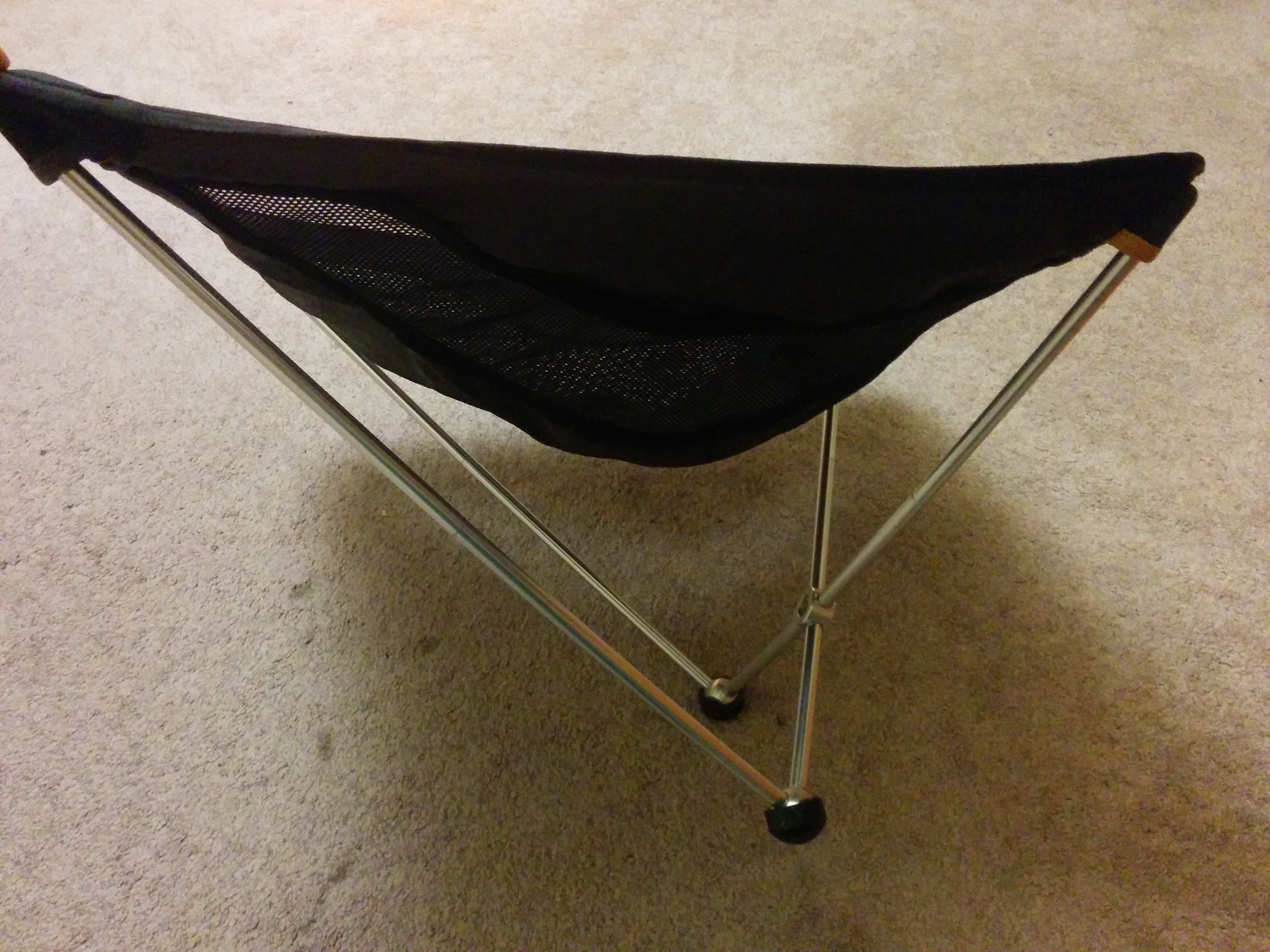 The camping chair from the side, with the two legs on the bottom and the seat above.
