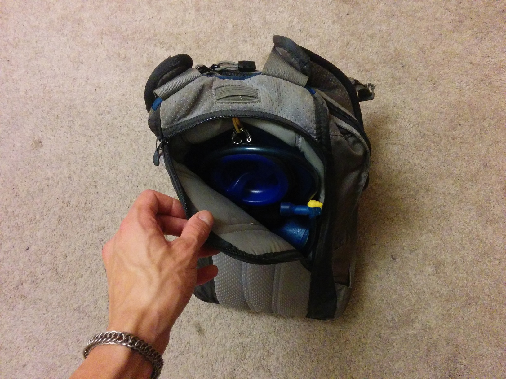 Showing the back compartment of the backpack, with a plastic water reservoir and tube inside.