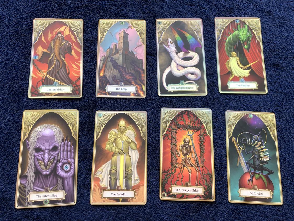 A handful of the 2e cards, The Inquisitor, showing a grand sorcerer holding a book, surrounded by chains, and the pages flying out of the book. This card, in the deck of many things, would allow the person who pulled this card to force anyone to answer any one question truthfully. The second card shown is The Keep, a grand castle on a mountaintop, defending itself from an attack with fiery balls being launched below. This would get you your own demiplane. The third is The Winged Serpent, the wish card, which shows a white snake with rainbow wings facing upwards on a cloudy background. The fourth is The Theater, showing a much more detailed fighter and dragon emerging from behind curtains, both held up by puppet strings. This would increase one of the drawers stats by 1. Bottom row, the fifth card is The Silent Hag, mentioned below in the text about the name change. An eyeless wrinkled, purple hag with stringy white hair holding an eyeball in her left hand. In the original card it was in her mouth. This would force the drawer to choose between being blind, deaf, or mute. The next is The Paladin, a majestic fighter with a white cape holding a golden sword. This card would bestow the drawer with the Holy Avenger sword. The seventh card is The Tangled Briar, which shows a skeleton sitting in a wooden frame with a red glowing background, with thorny vines coming from the top and the bottom gripping the frame. This card would let you speak to plants, and they would have to answer any question truthfully, but it would in return summon shambling mounds for you to fight. The last card shown is The Cricket, which shows a black cricket playing with a deck of cards in front of a dark, starry background, sitting atop an apple with a sword in it. This card would allow the drawer to pull up to three more cards, and with each additional card, their speed would increase by 10 feet.