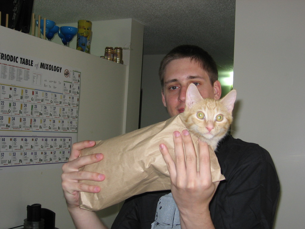 Kris holding up Jack, inside of a small paper bag.