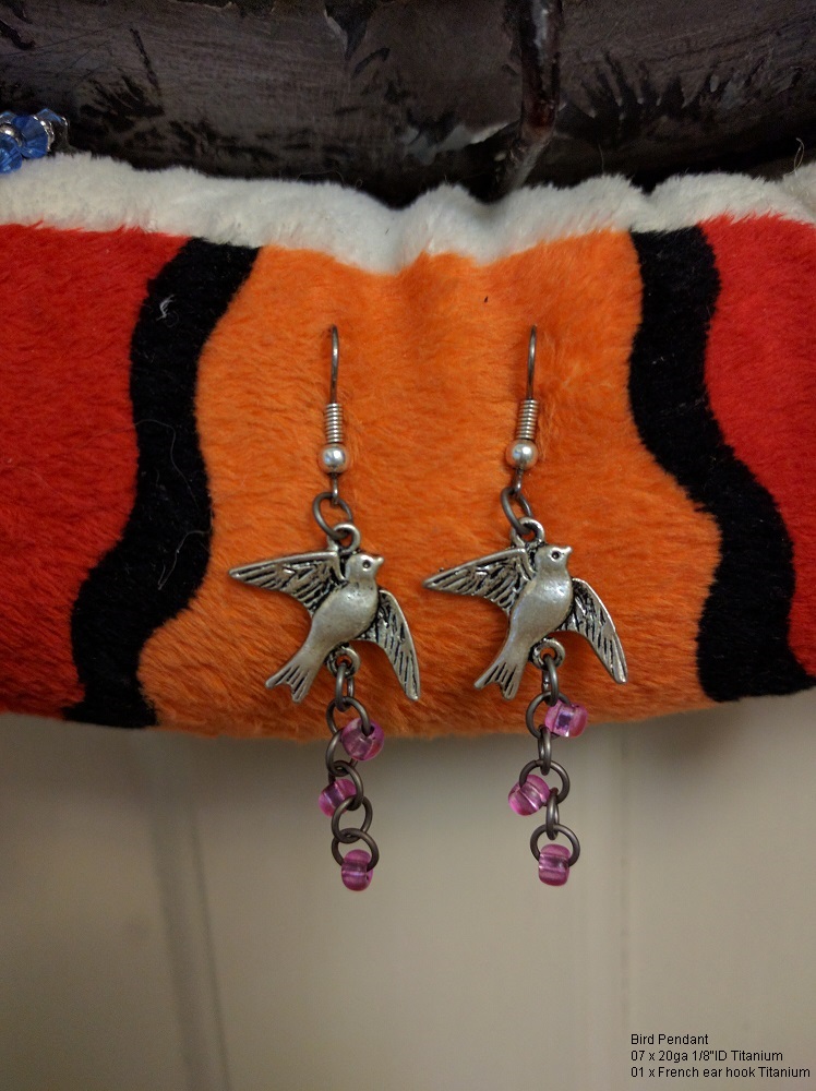 A pair of earrings with bird pendants, and little pink beads.