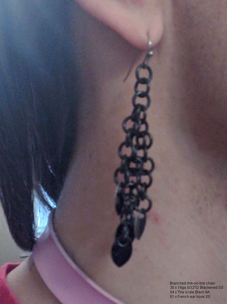 A blackened chainmaille dangley, with mini scales at the bottom.