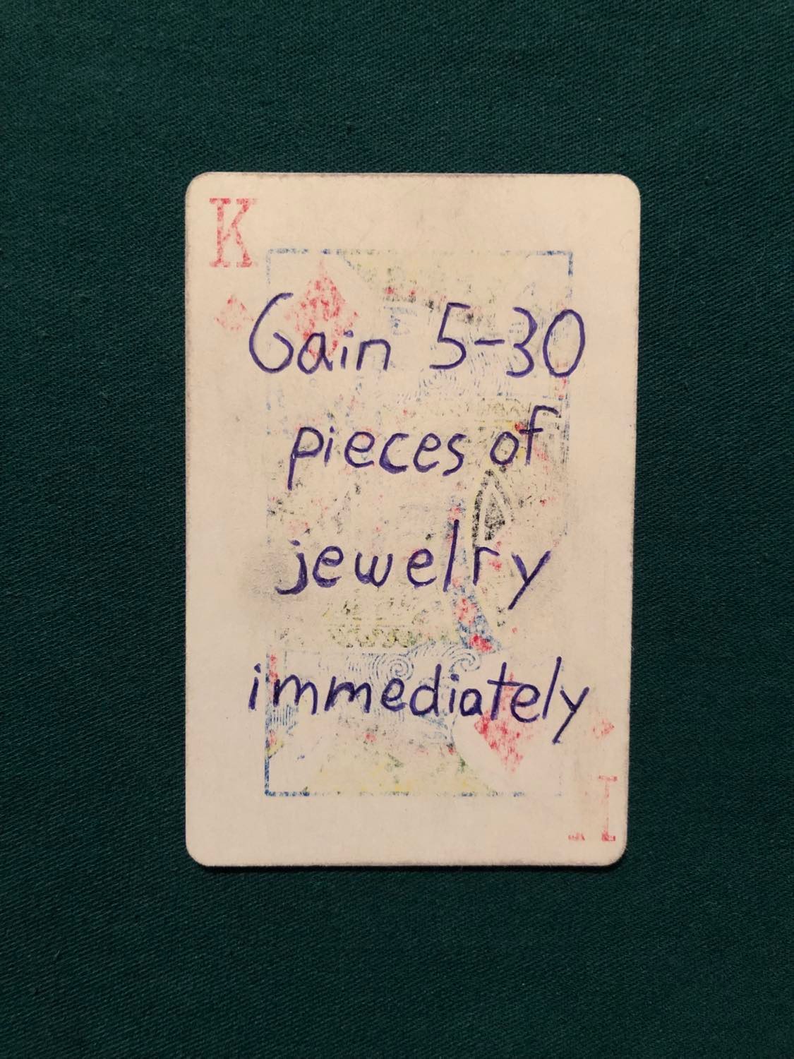 The king of diamonds, laying on a green fabric.
