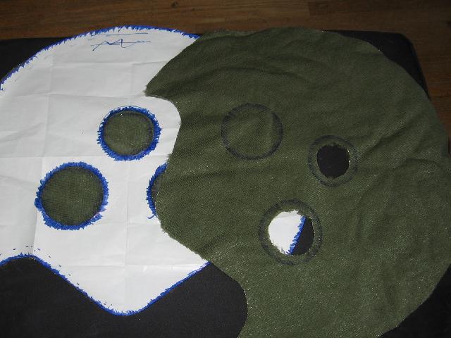 Holes cut in the green fabric, where the red orbs will go.