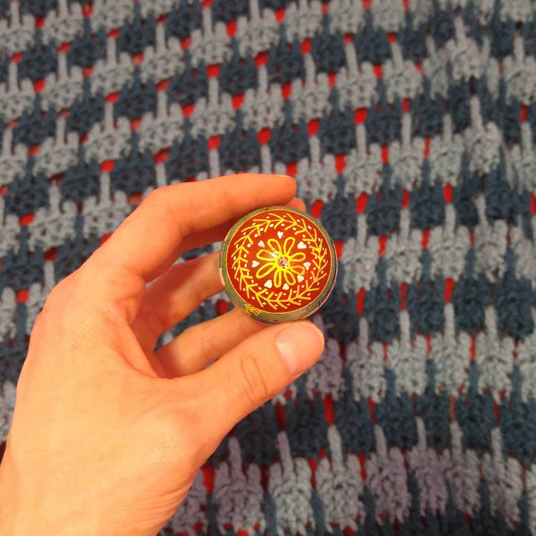 The bottom of the egg, red with yellow lines, showing a linework flower and hearts.