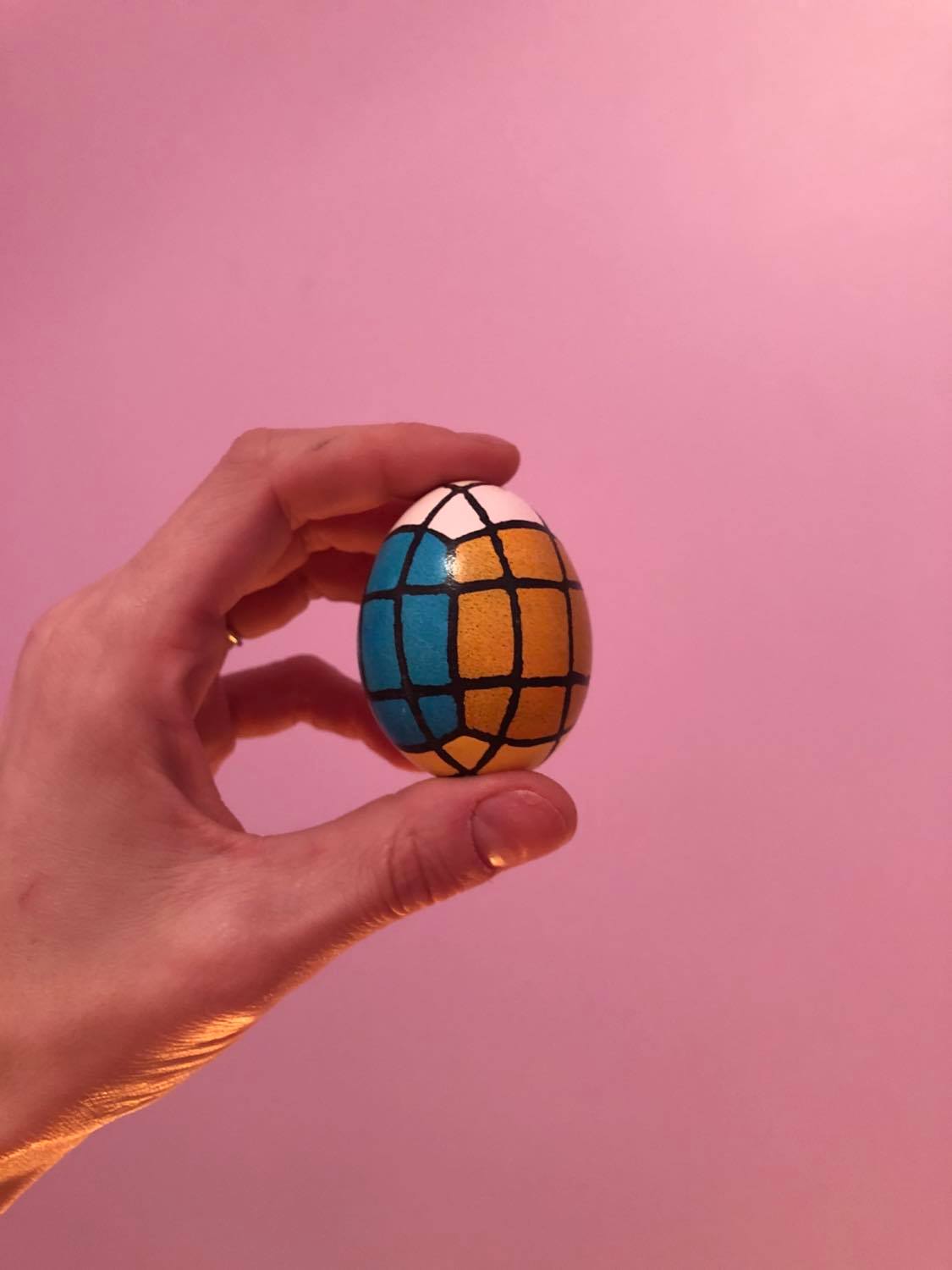An egg with black linework and coloured squares, as though a rubik's cube had been stretched into the shape of an egg.