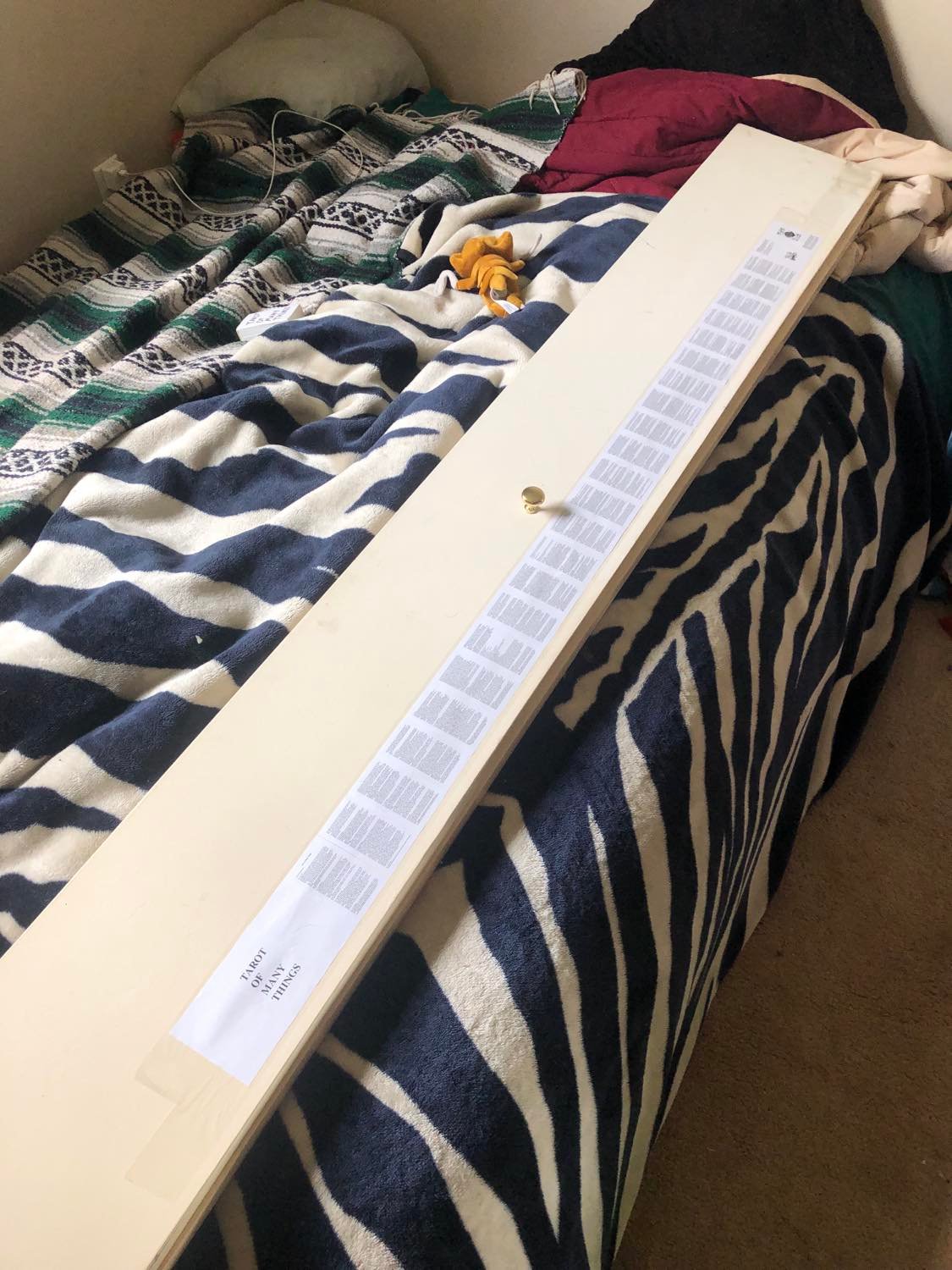 The better method, sticky-side-up tape layed across a long board, and held taut on either side, and all of the pages of the book are attached to the tape. The board in question here is a closet door, read below for details. It's sitting on a zebra-print blanket, on a bed. A Kabutops doll is kinda crawling around on the bed.
