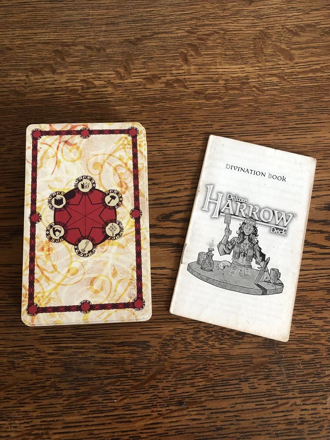 The Harrow deck cards and instruction manual beside, on a wooden desk.