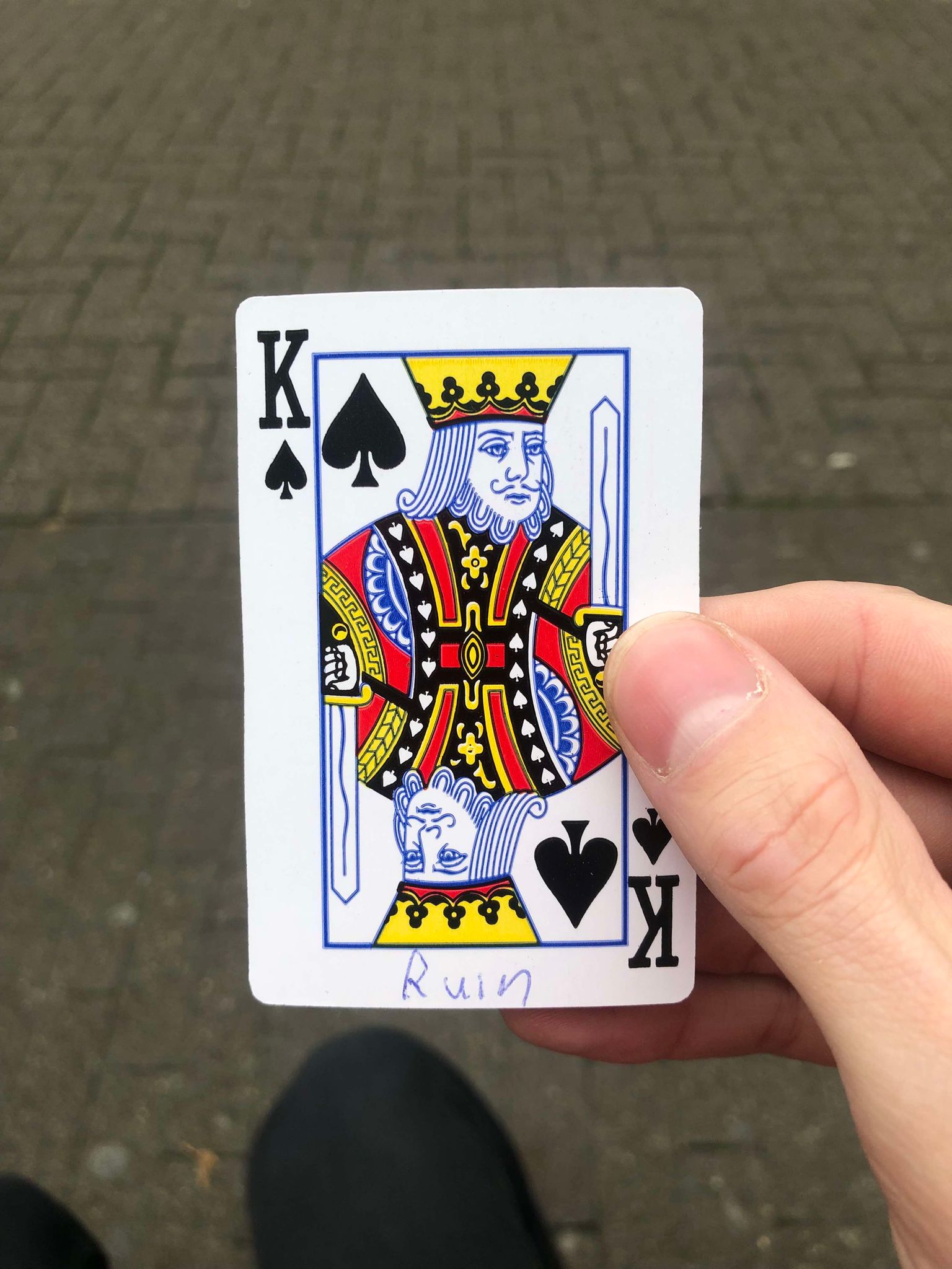 Sitting on a bench, a brick walkway in front of you, you hold the drawn card in front of you.