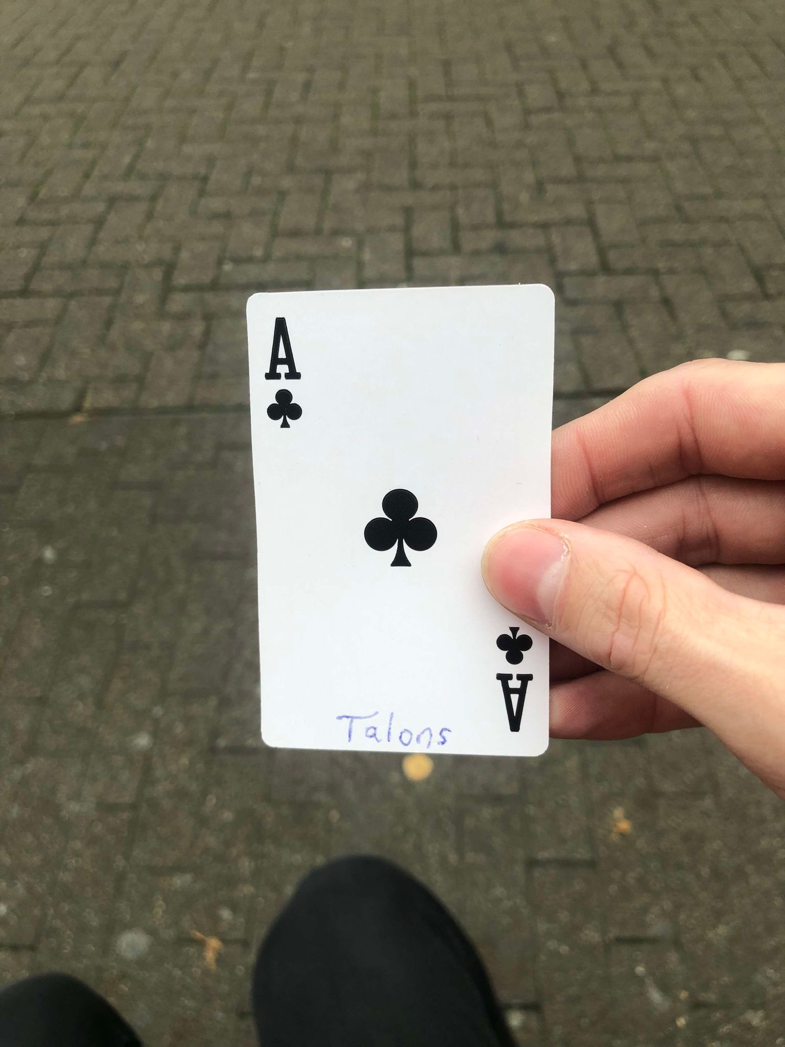 Sitting on a bench, a brick walkway in front of you, you hold the drawn card in front of you.