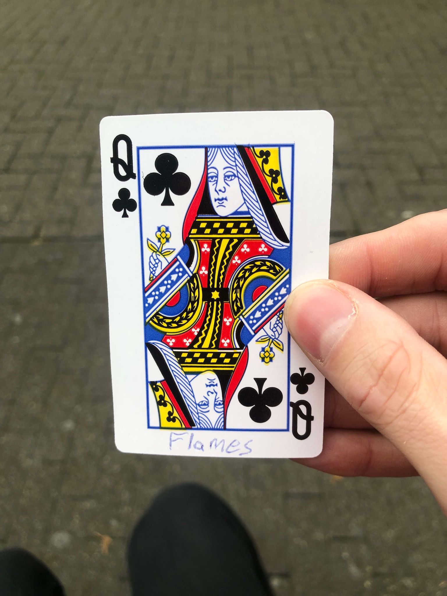Sitting on a bench, a brick walkway in front of you, you hold the drawn card in front of you.