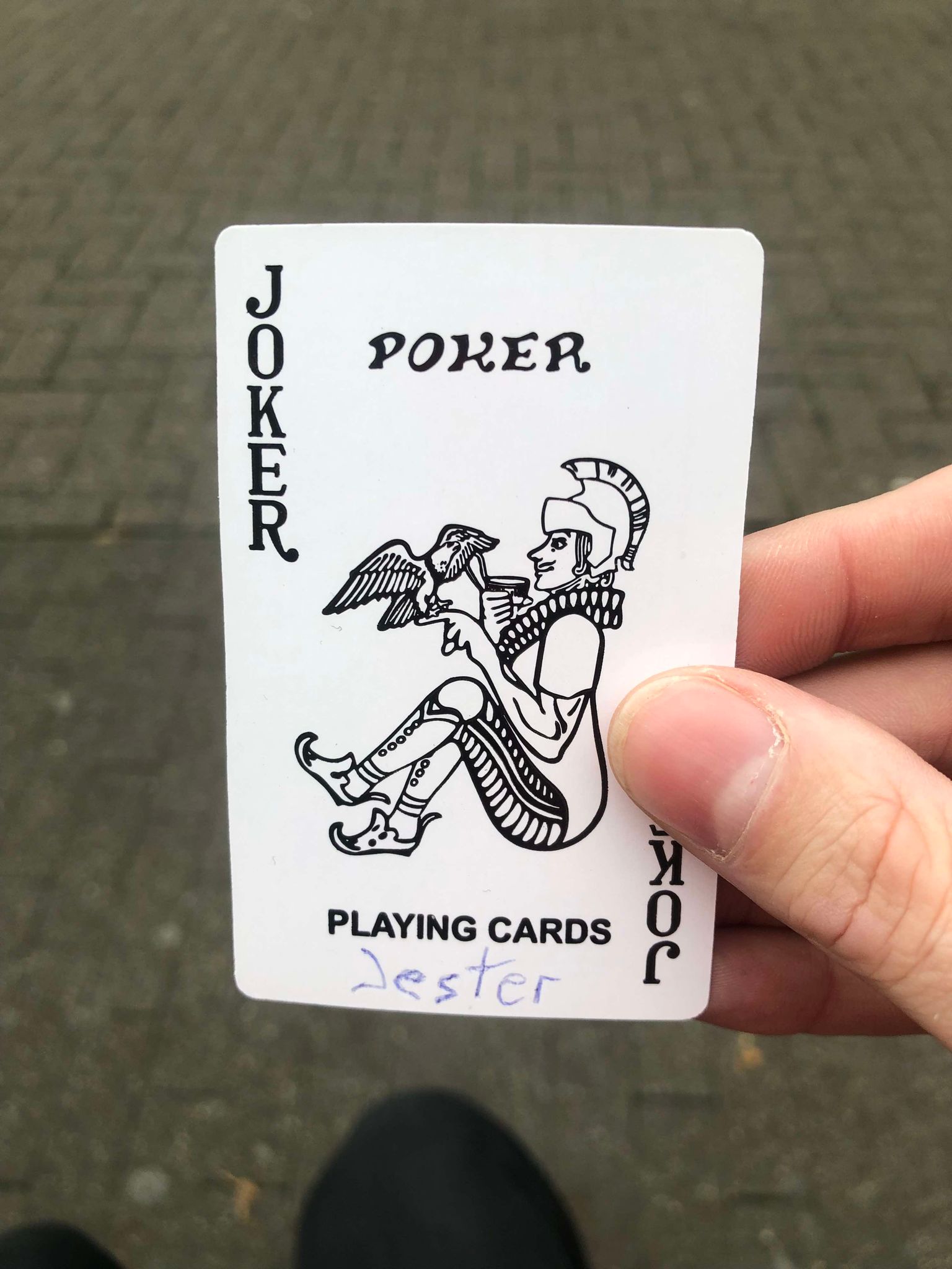 Sitting on a bench, a brick walkway in front of you, you hold the drawn card in front of you.