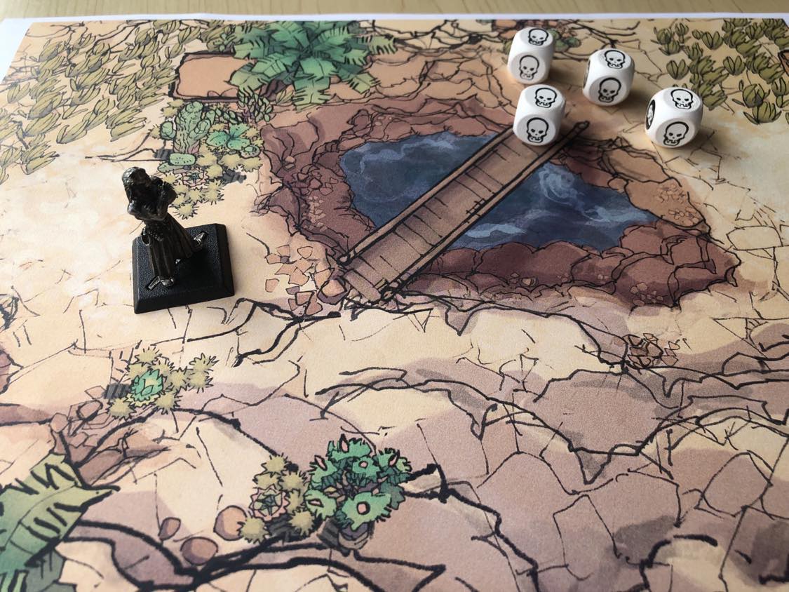 A battle map on a wooden table, a mountainous terrain with a bridge over a deep pit of water. Four skull dice representing skeletons block your path across the bridge and begin to approach.