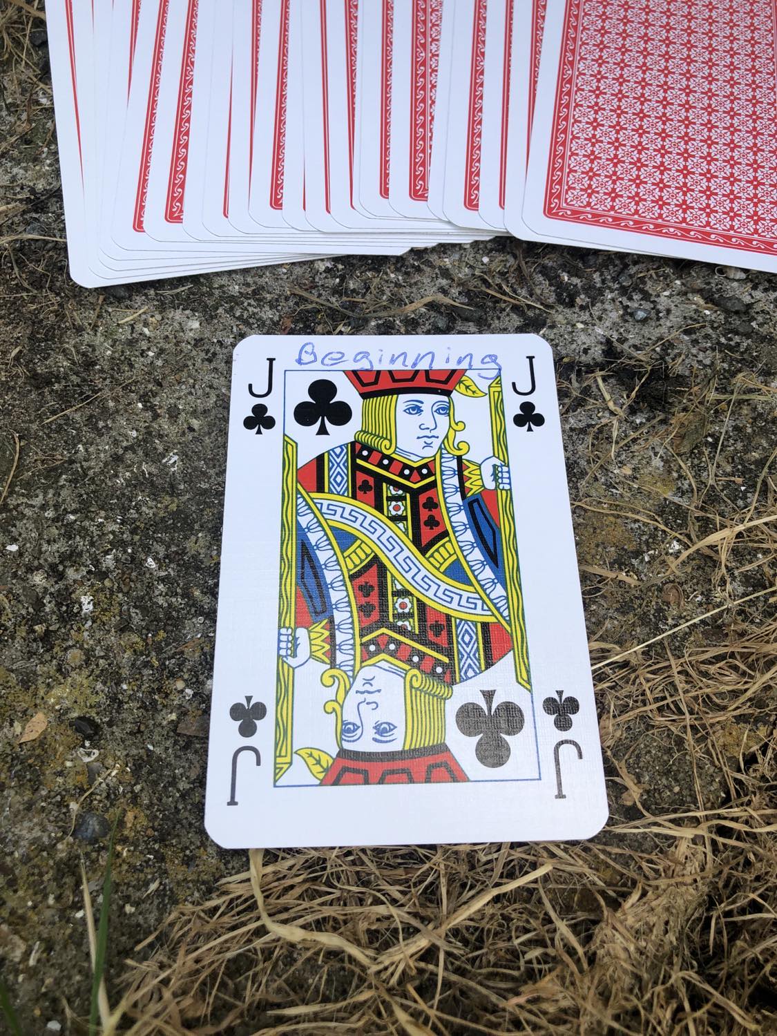 The jack of clubs with the word Beginning written on it, laying on the bridge support.