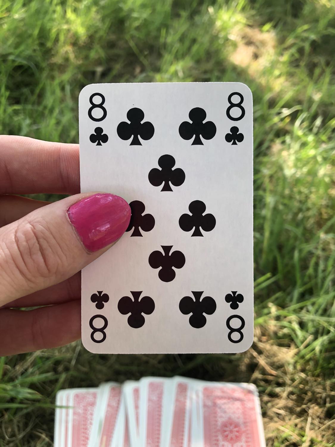 The eight of clubs, held up from the drawn out cards.