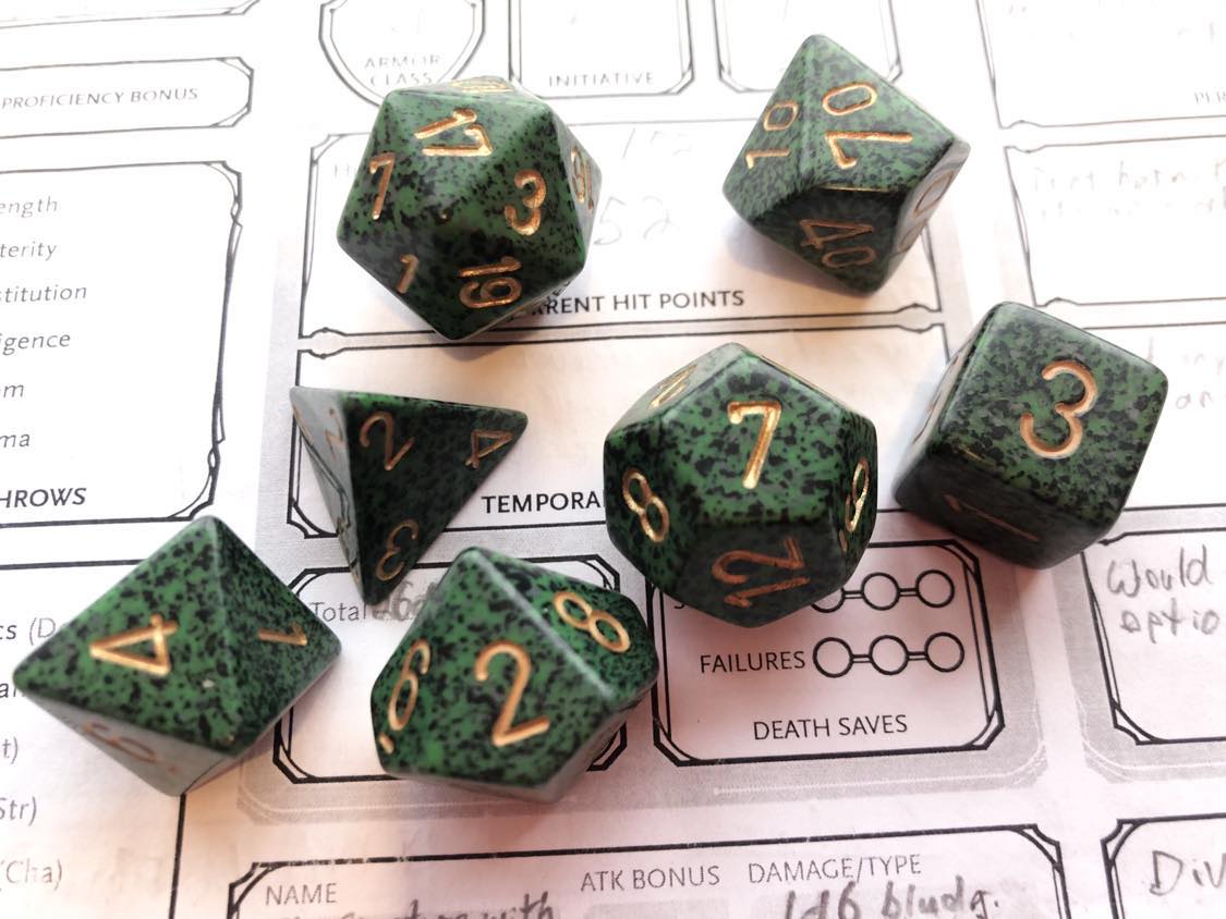 Dark green dice of the Chessex speckled recon gold pattern, which has very small and many black speckles throughout it, with gold lettering, sitting on a character sheet.