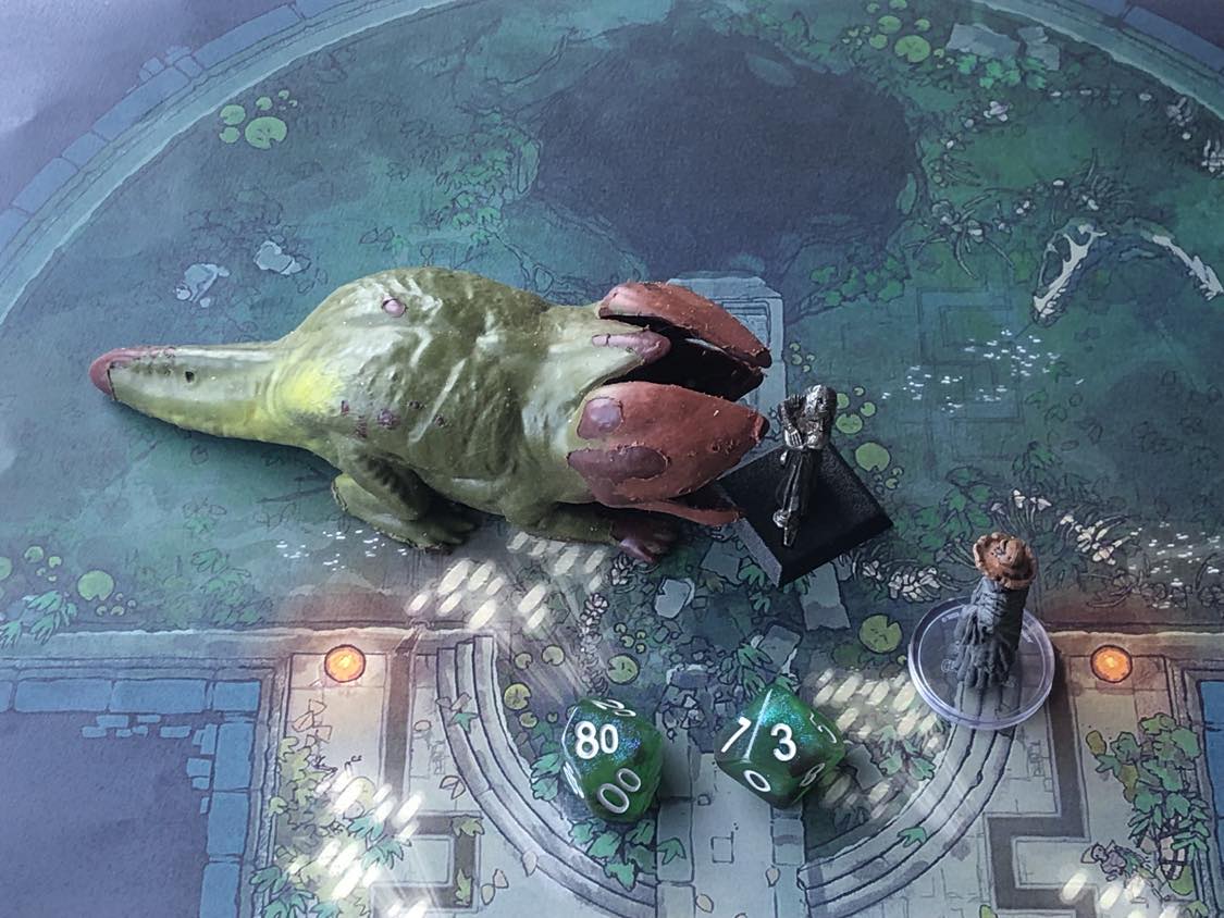 The battle map from above, with the monk fully attacking the creature, and the sorcerer rolling a pair of d10 dice to determine the wild magic surge.