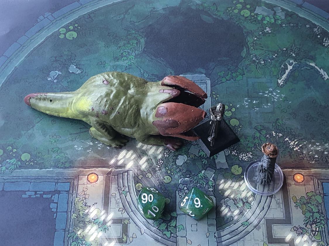 The battle map from above, with the monk fully attacking the creature, and the sorcerer rolling a pair of d10 dice to determine the wild magic surge.